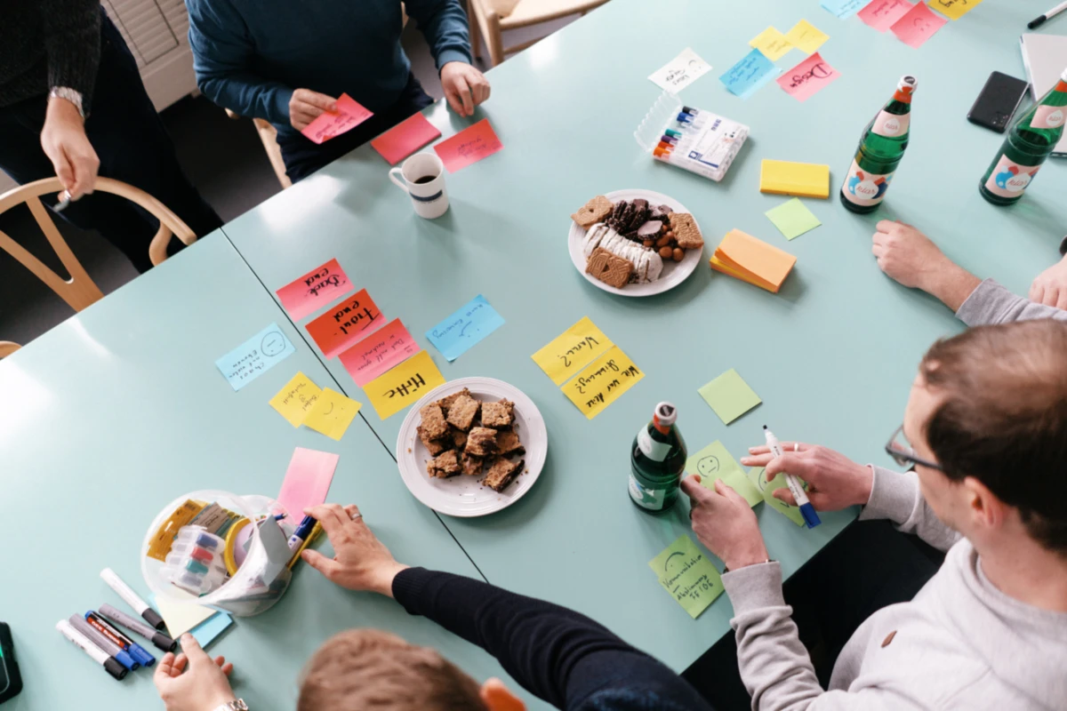 Projektteam sitzt um Tisch mit Klebezetteln und plant Projekt.