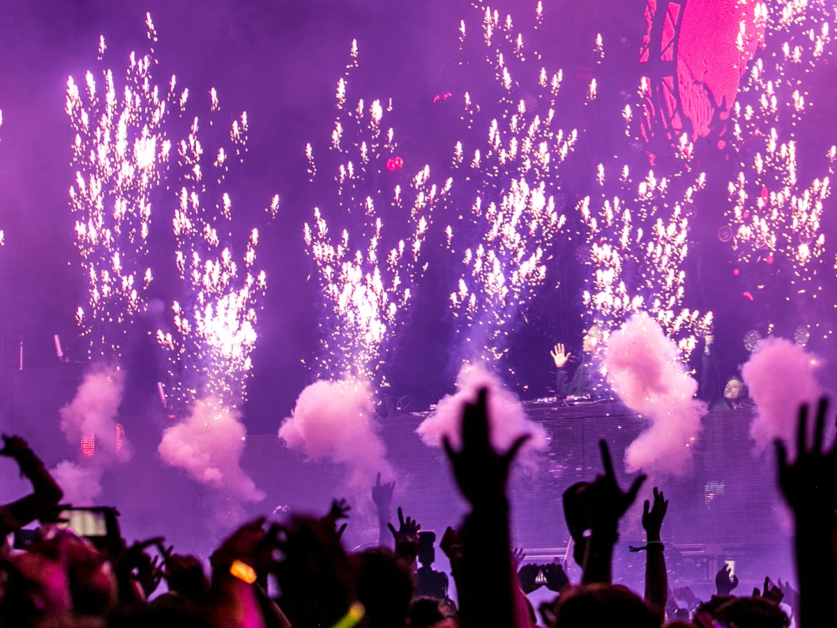 Menschenmenge jubelt bei Konzert vor Bühne, auf der Feuerwerk abbrennt