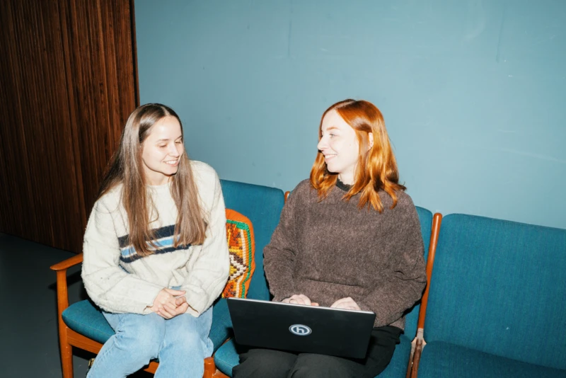 Zwei Mitarbeiterinnen besprechen sich mit Laptop auf Sofa 
