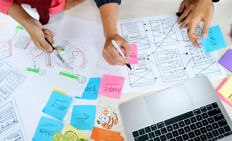 PHP Symfony: Projektteam plant auf Papier und Klebezetteln den Aufbau einer Website.